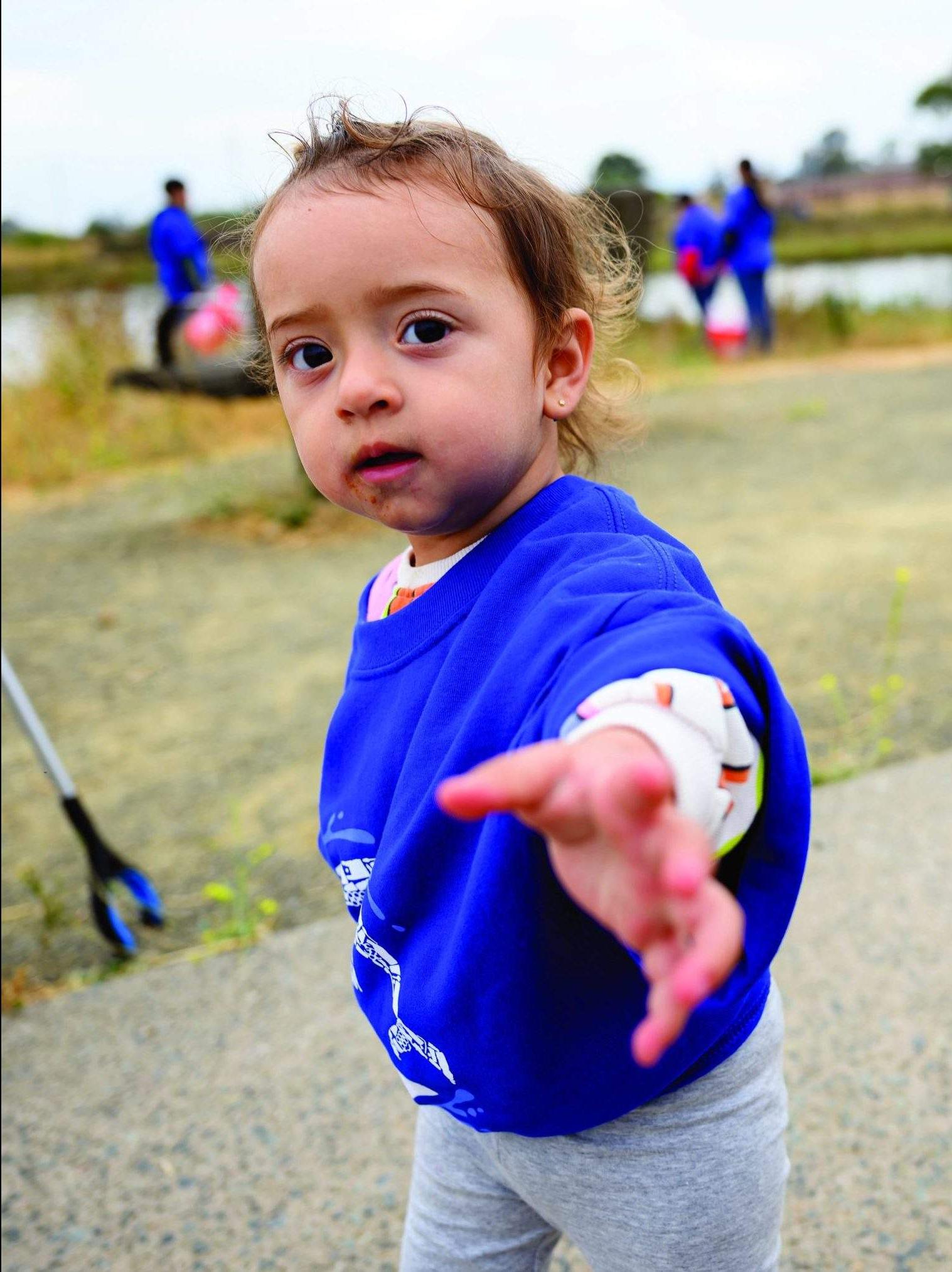 A toddler wearing a blue 澳博体育app下载 "Sea The Change" t-shirts gives a helping hand at the Oakland Estuary.